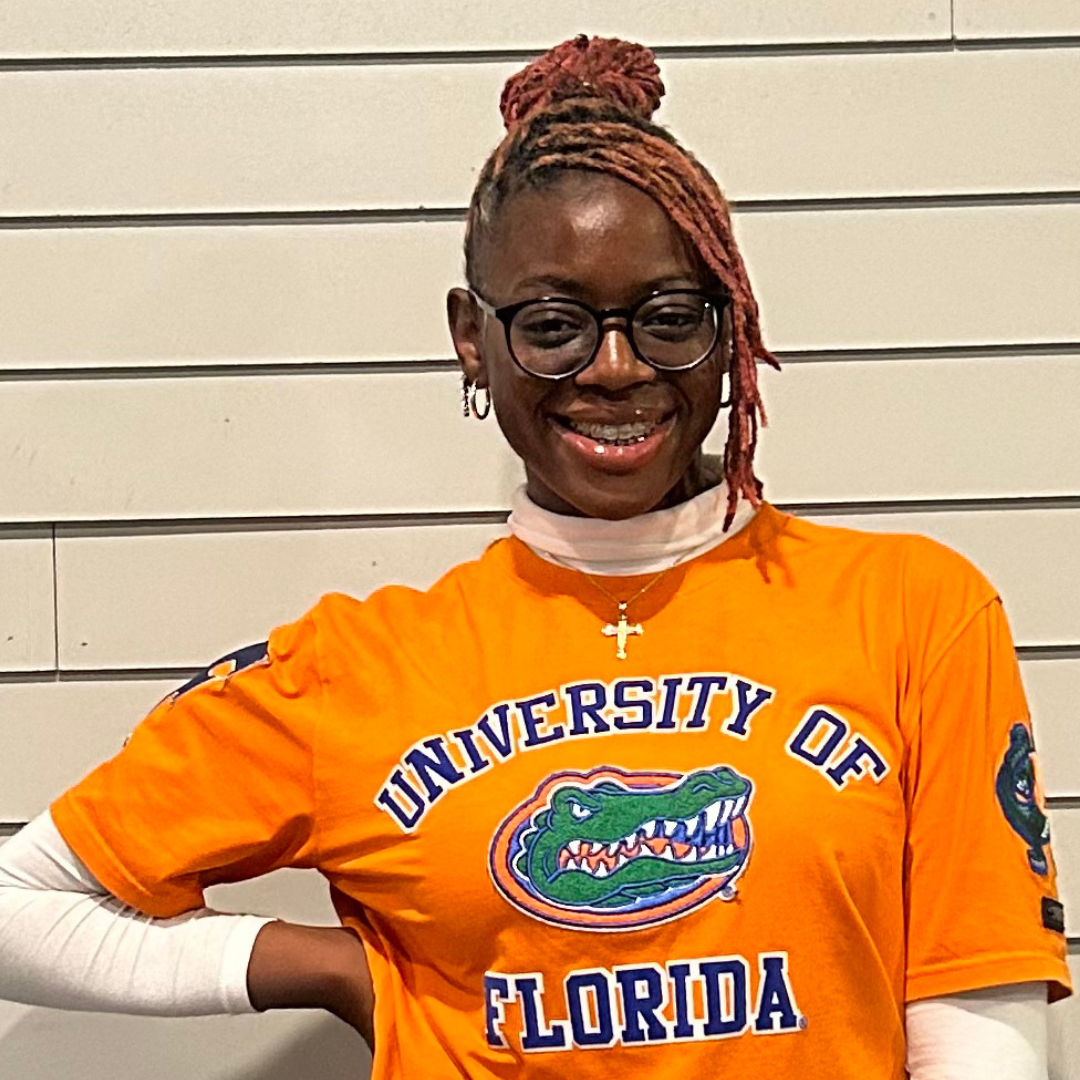 Young person smiling, wearing glasses, braces, and an orange "UNIVERSITY OF FLORIDA" t-shirt featuring the Gator logo.